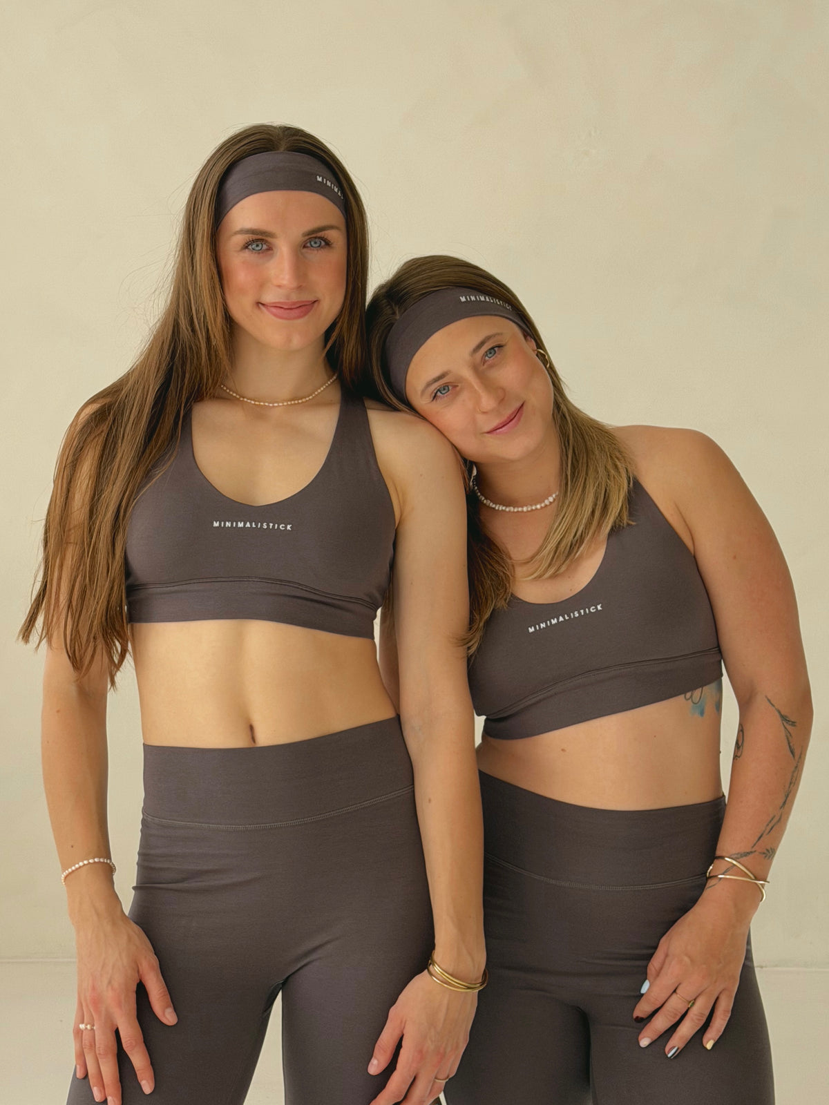 Dvě modelky s tmavě šedými sportovními čelenkami z organické bavlny MINIMALISTICK, pohled zepředu.