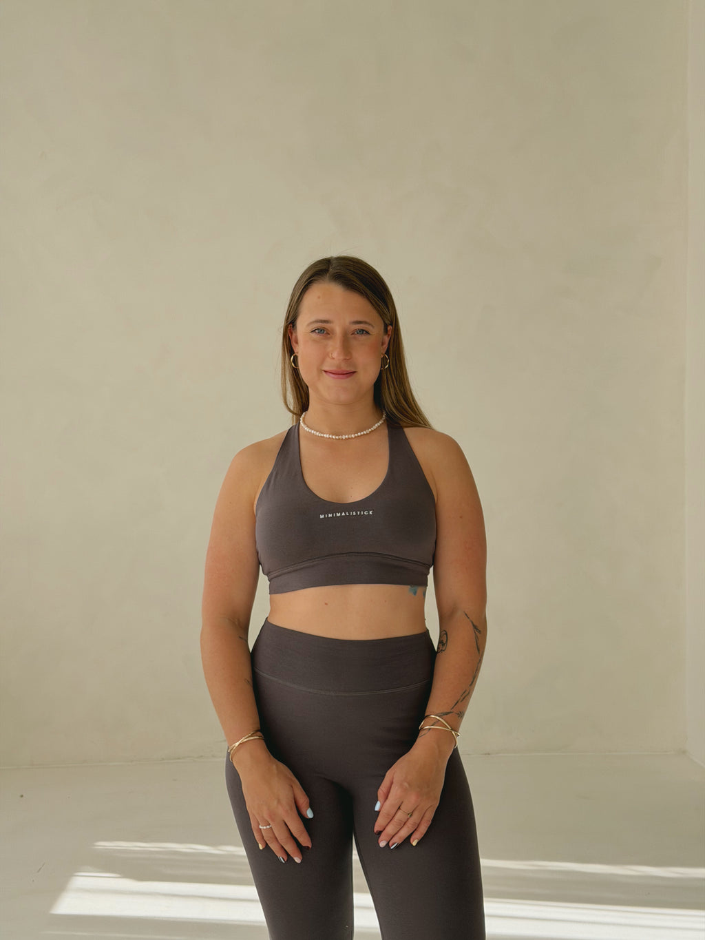 Sportovní podprsenka z organické bavlny v tmavě šedé barvě, na modelce v kombinaci s legínami.